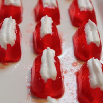 Strawberry Daiquiri Jello Shots on a white platter garnished with whipped cream