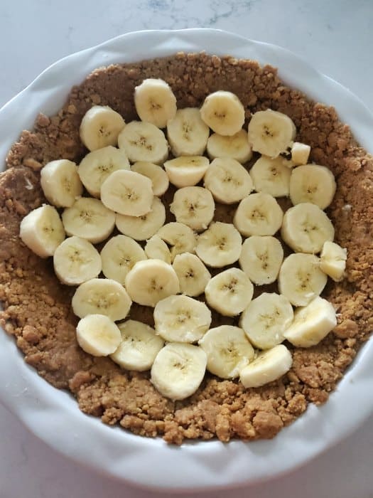 Sliced bananas on a nutter butter crust in a white pie plate