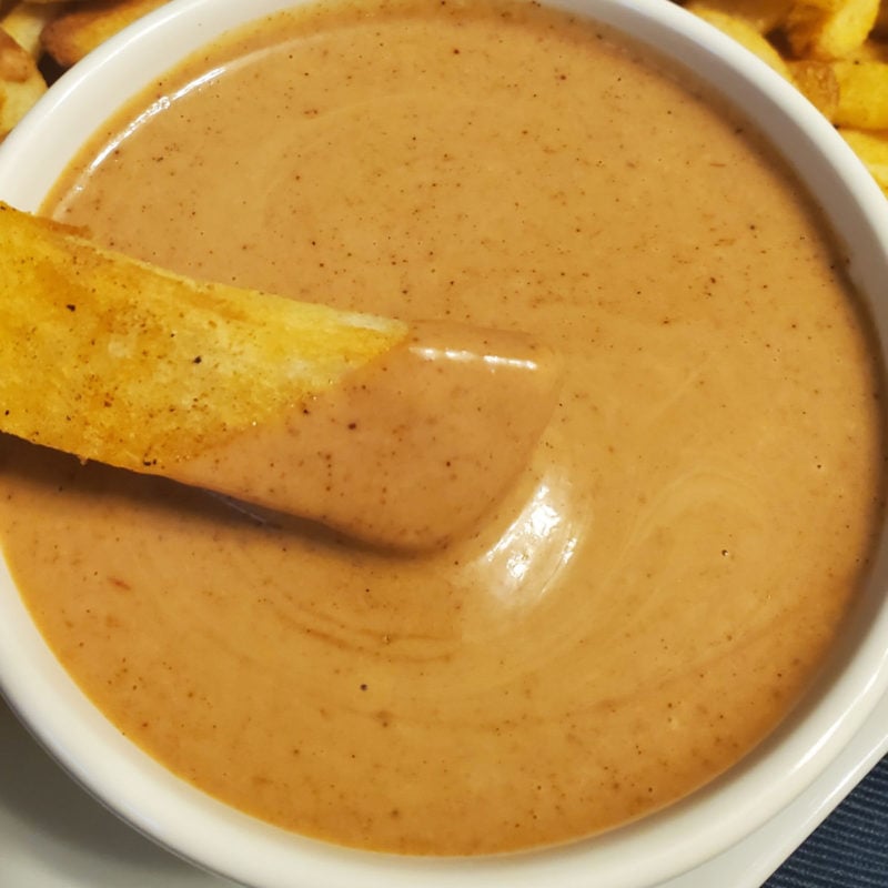 French fry dipping into a bowl of Red Robin Campfire Sauce