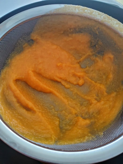 carrot puree going through a strainer