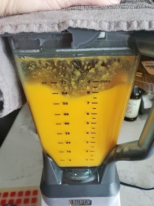 orange liquid in a blender with a towel over the top of it