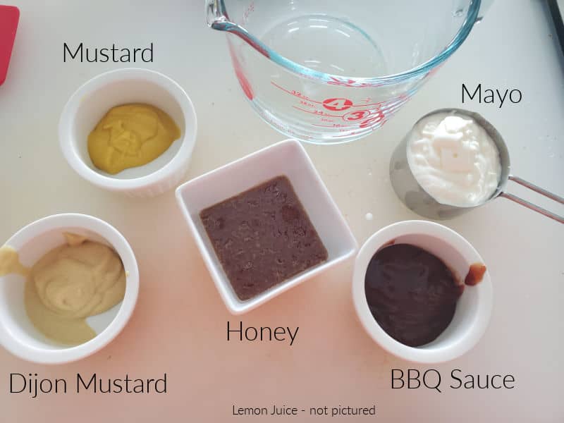 Mustard, mayo, bbq sauce, honey, and dijon mustard in bowls on a counter. 