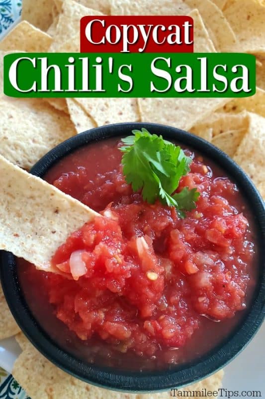 Copycat Chili's Salsa in a black bowl with a tortilla chip in it. 