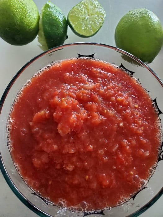 Chili's salsa in a glass bowl with limes next to it. 