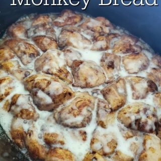 Crockpot Cinnamon Roll Monkey Bread over a slow cooker with cinnamon rolls and icing