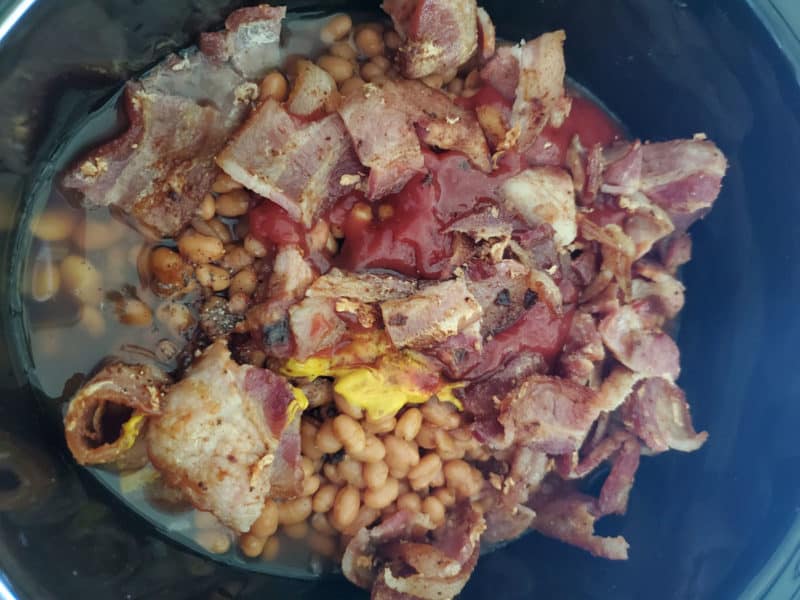 Bourbon baked beans ingredients piled together in a slow cooker before stirring