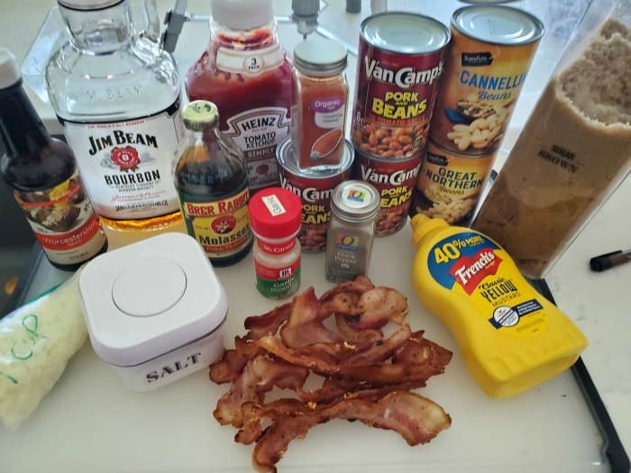 Worcestershire Sauce, bourbon, ketchup, molasses, baked beans, spices, mustard, salt, and bacon on a white counter
