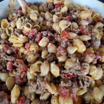 Tex Mex Velveeta Shells and Cheese in a white bowl with a wooden spoon