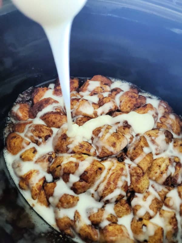 icing pouring over cinnamon roll monkey bread in the slow cooker