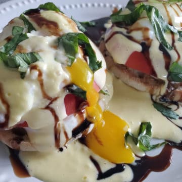 Caprese Eggs Benedict with egg yolk running down the side