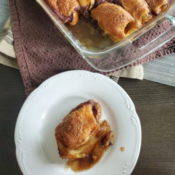 Apple Pie Dumpling on a white plate next to a glass baking dish