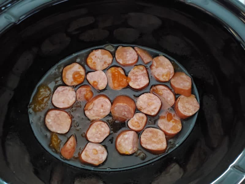 Sliced kielbasa in a slow cooker bowl with sauce