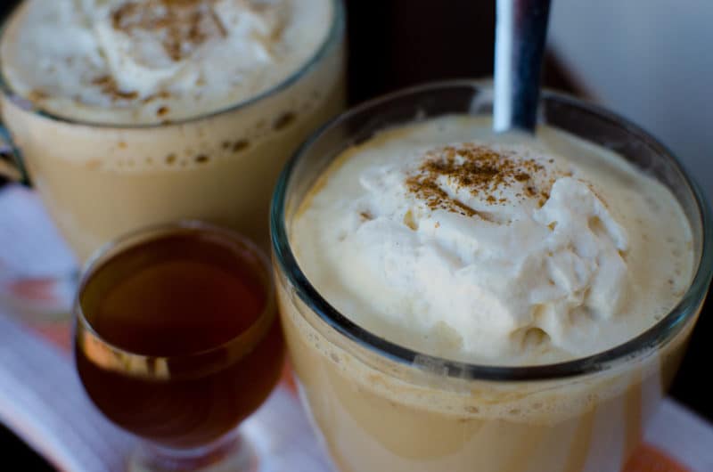 latte in a glass coffee mug next to a 2nd mug