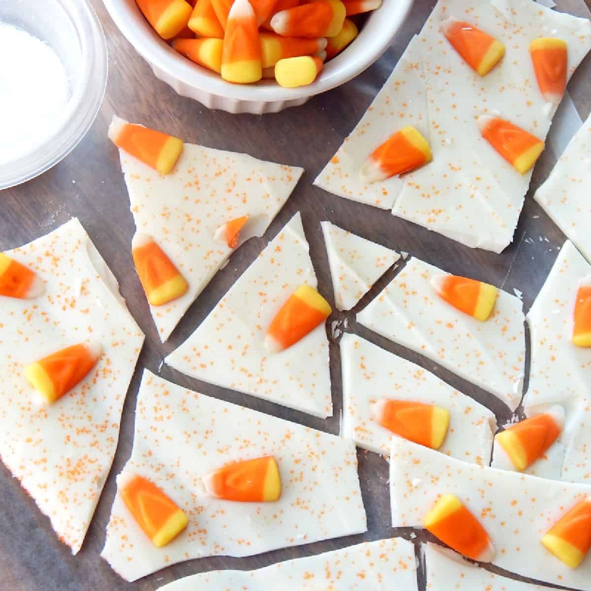 candy corn bark on parchment paper next to a bowl of candy corn