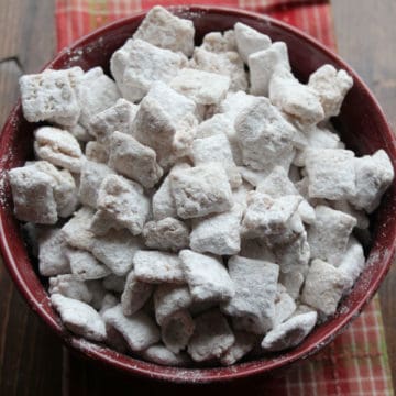 Apple Cider Muddy Buddies in a burgundy bowl on a wood board