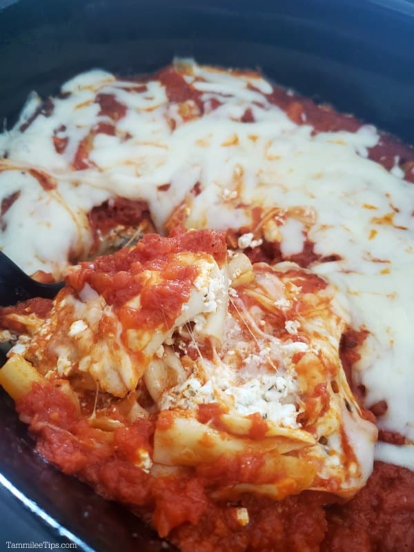 cheesy baked ziti on a spoon lifting out of a slow cooker