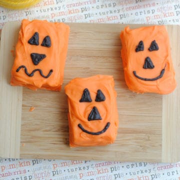 pumpkin rice Krispie jack o lanterns on a wood cutting board