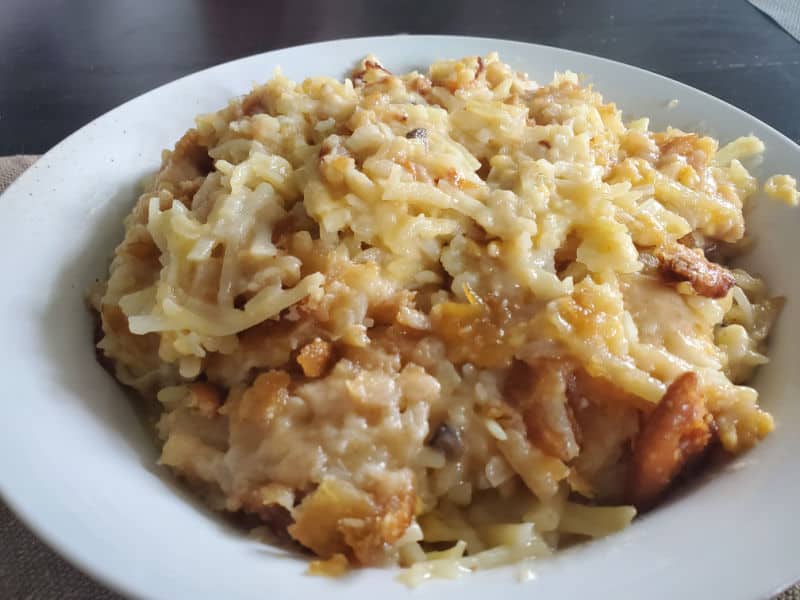 cheesy hashbrowns in a white bowl on a dark table