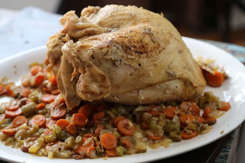 Turkey surrounded by carrots and celery on a white serving platter