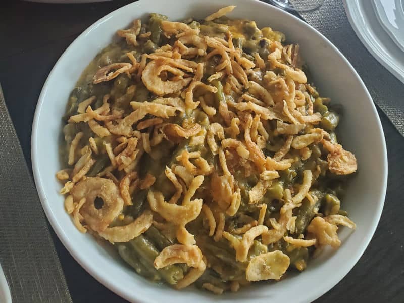 crockpot green bean casserole with fried onions on top in a white bowl