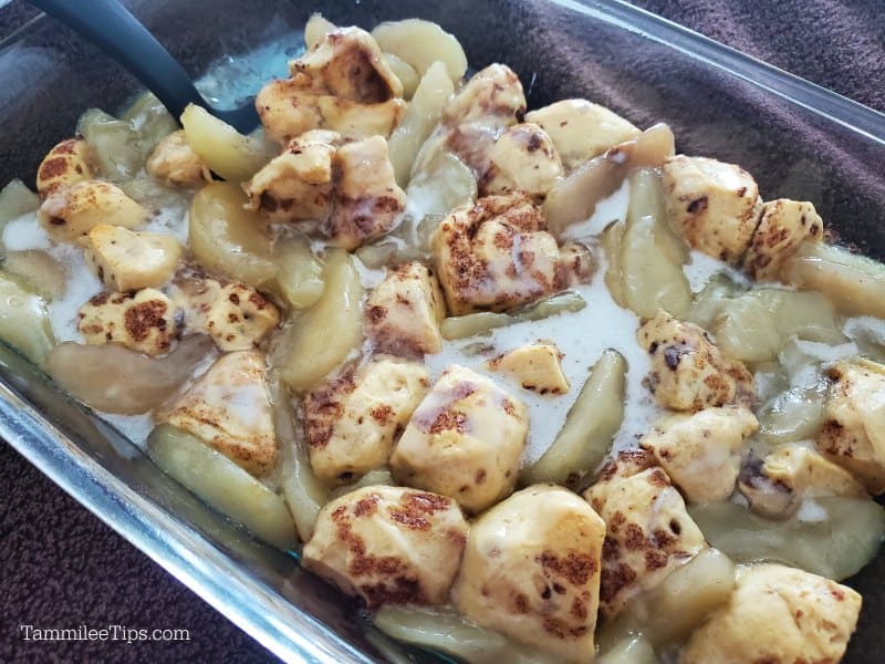 Cinnamon roll pieces and apples covered in glass baked in a glass baking dish