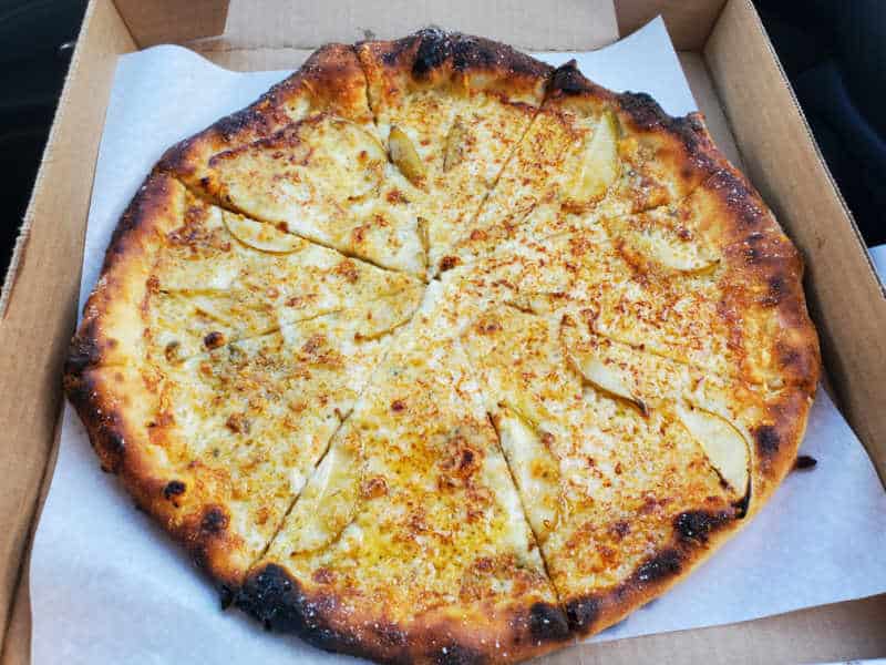 cheese and pears on a pizza in a cardboard delivery box