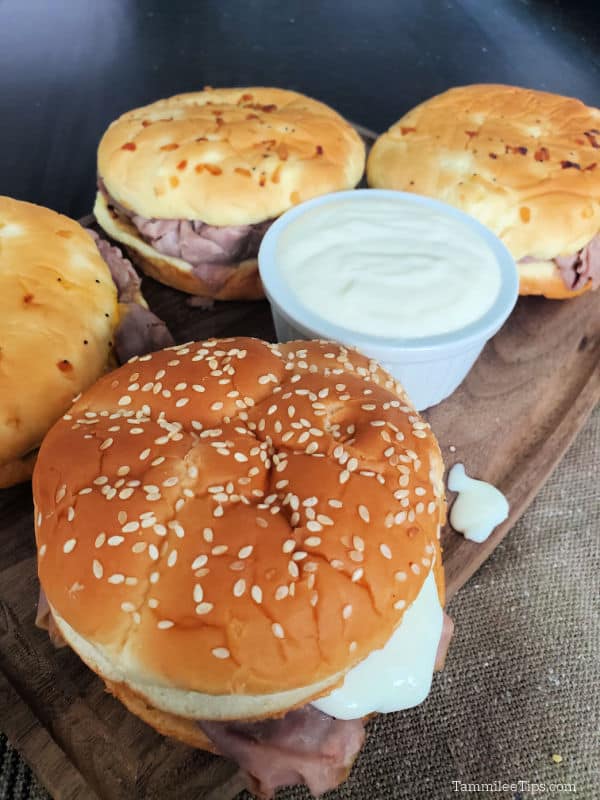 Arby's horsey sauce in a white bowl next to Arby's roast beef sandwiches. 