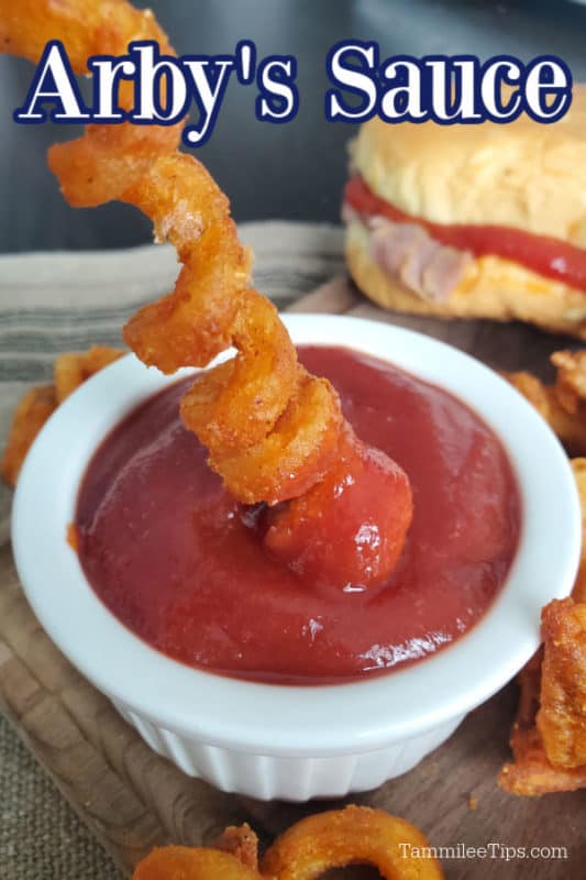 Arby's sauce over a curly fry dipping into a bowl of Arbys sauce. 