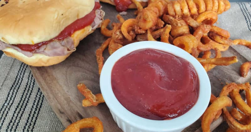 arby's sauce in a bowl next to curly fries and an Arby's roast beef sandwich. 
