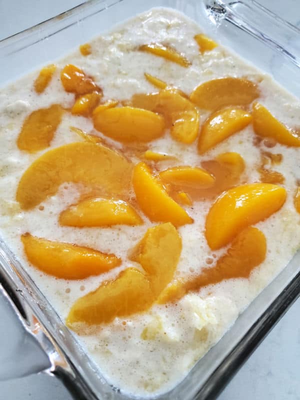 peaches in batter in a glass baking dish. 