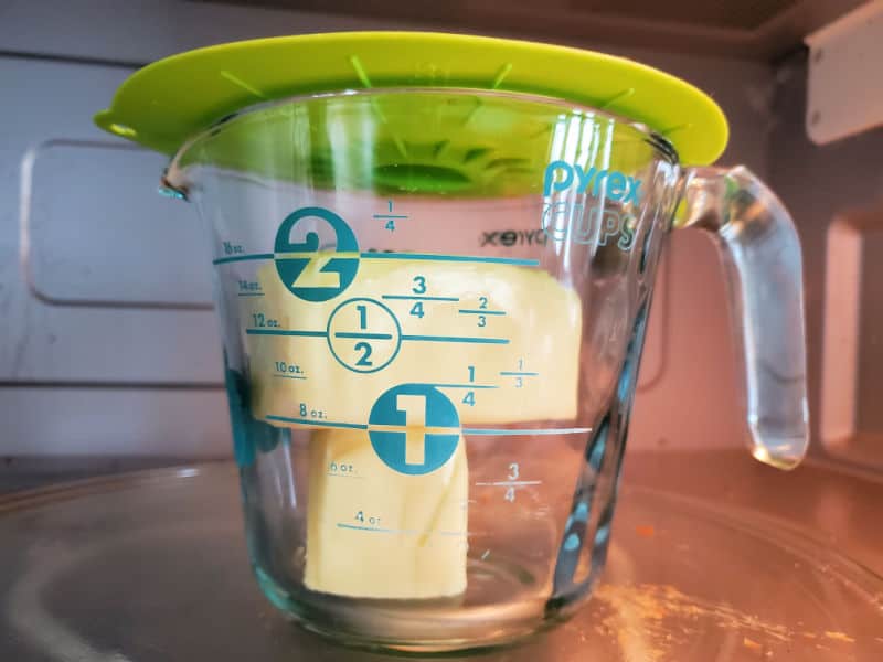 butter in a measuring cup with a plastic cover over it