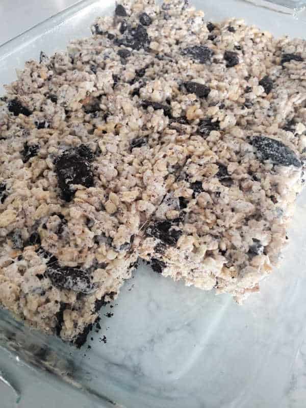 Oreo Rice Krispies in a glass baking dish with one square missing. 