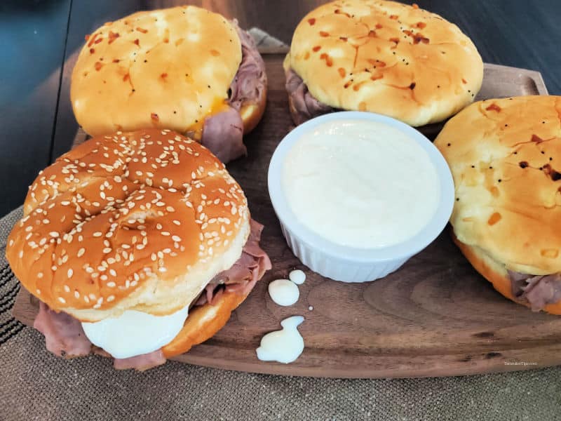 Horsey sauce in a white bowl next to Arby's roast beef sandwiches. 