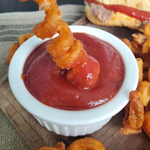 curly fry dipping into Arby's Sauce in a white bowl