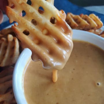 Waffle dry dipping into Chick fil a sauce in a white bowl