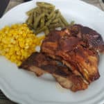 dr pepper ribs next to corn and green beans on a white plate