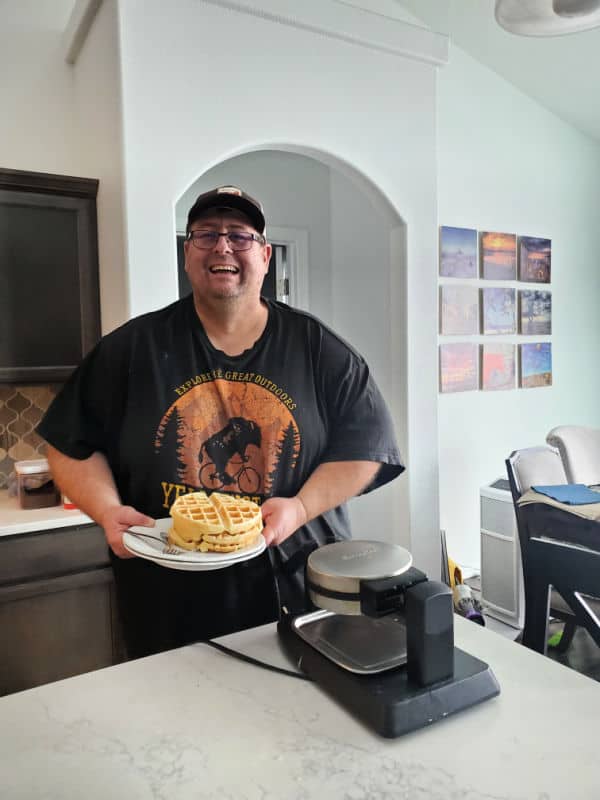 Park Ranger John holding a plate of bisquick waffles by the waffle maker