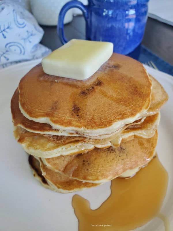 Stack of muffin mix pancakes on a white plate next to a blue coffee mug