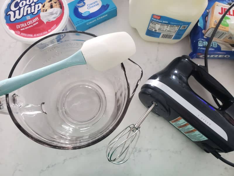 Glass bowl, spatula, hand mixer, cool whip, cream cheese, milk and jello for Oreo Fluff