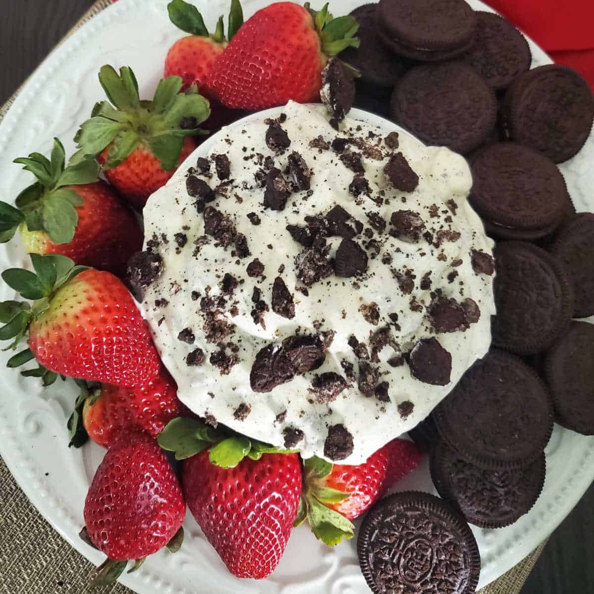Oreo Fluff in a white bowl next to strawberries and oreo cookies