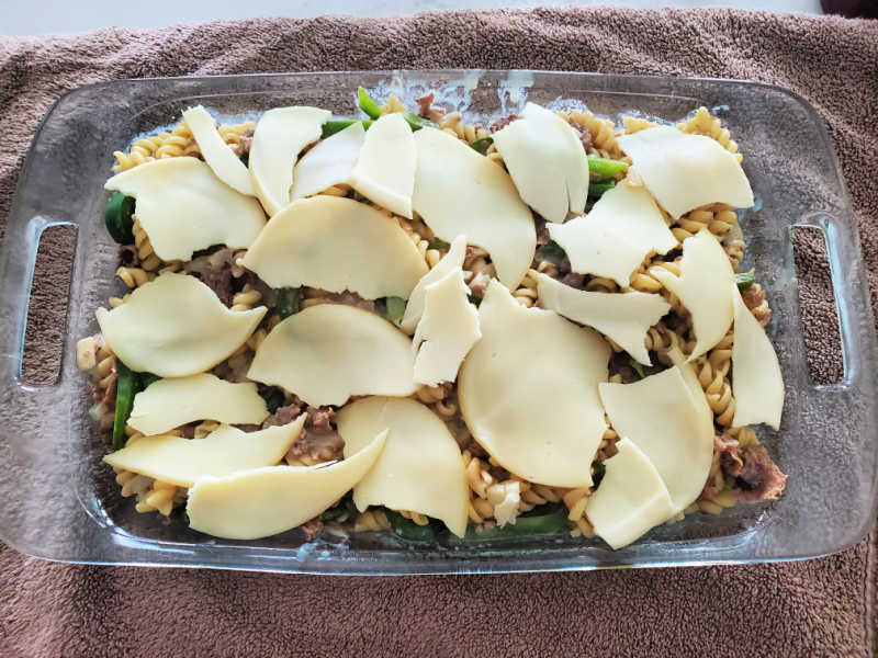 provolone cheese slices over philly cheese steak casserole in a baking dish