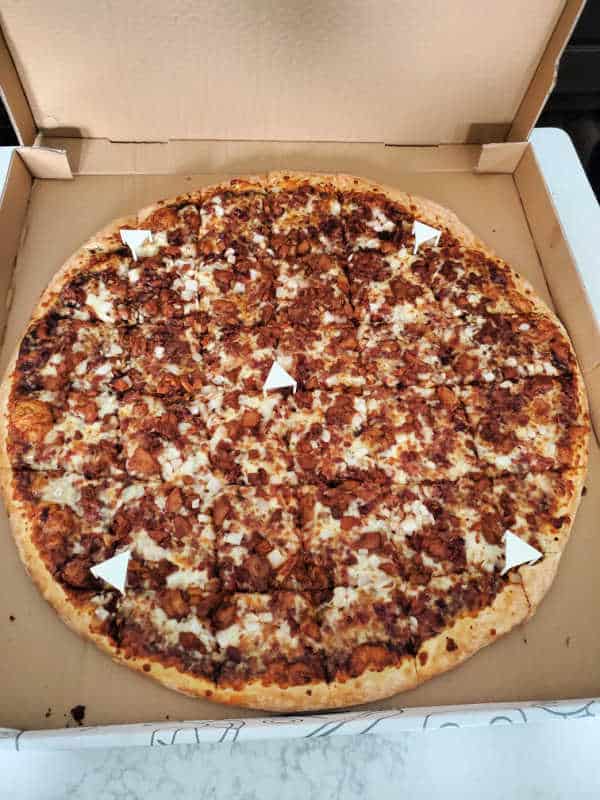 Pizza covered in meat in a cardboard delivery box