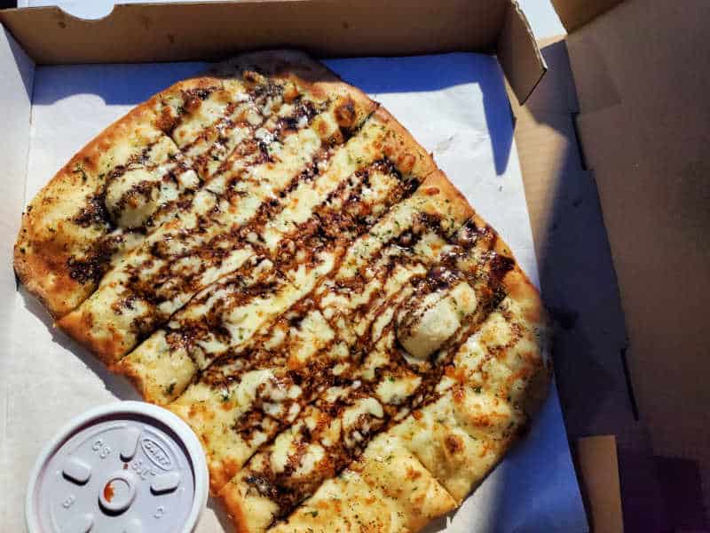 Cheese bread covered in a balsamic drizzle in a cardboard delivery box