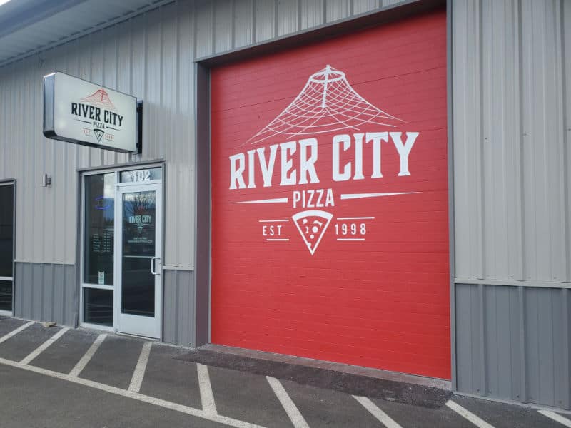 Exterior of River City pizza with large red door
