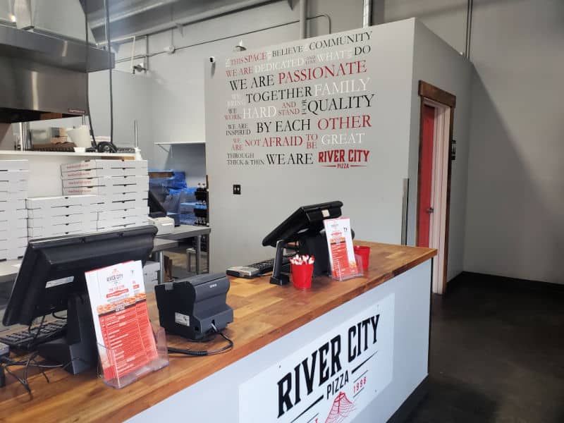 River city pizza sign on a counter with cash registers