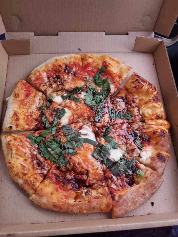 pizza with basil and cheese in a cardboard pizza delivery box