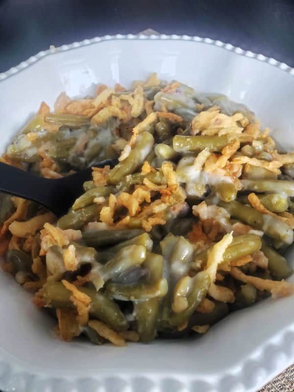 campbells green bean casserole in a white serving bowl with a black spoon