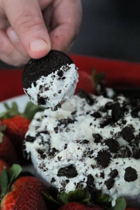 Oreo cookie dipping into Oreo fluff next to strawberries