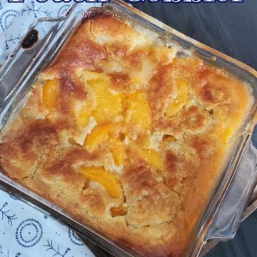 Bisquick Peach Cobbler in a glass dish next to a cloth napkin