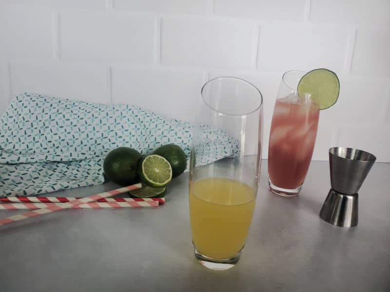 How to make a bay breeze cocktail, orange juice in a highball glass, cocktail jigger next to it. 
